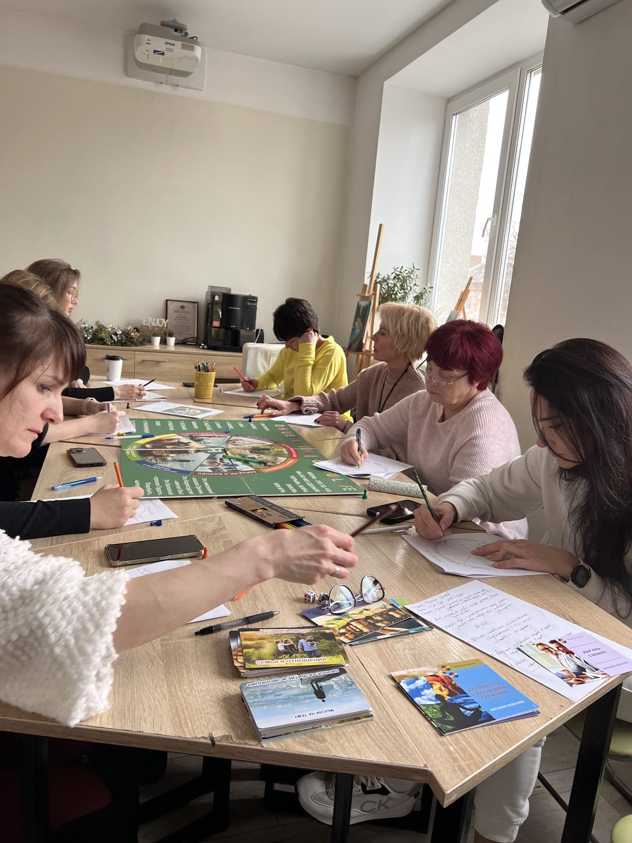 Учасники групи в обіймах кола під час трансформаційної гри в світлій залі